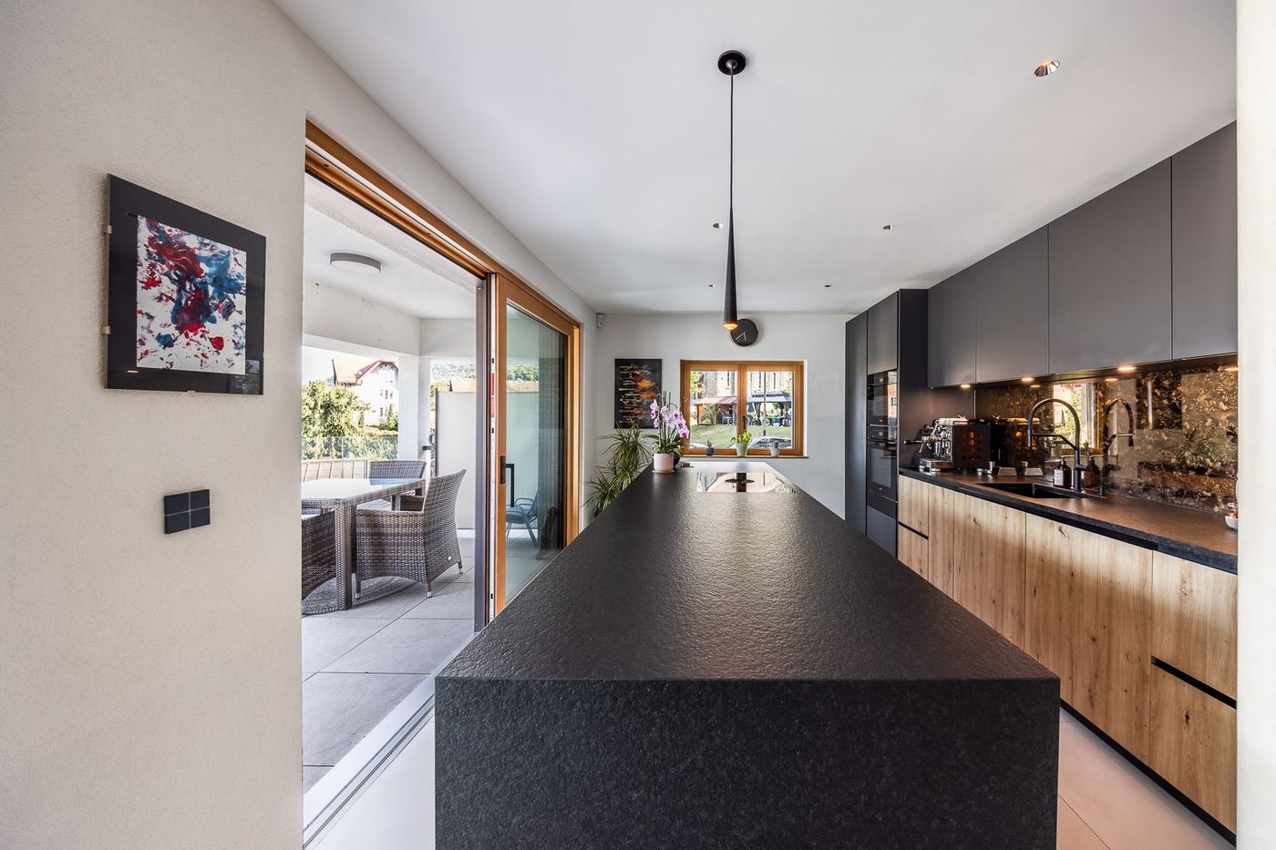 Cuisine contemporaine avec îlot en pierre et façades chêne — rénovation Le Bouveret